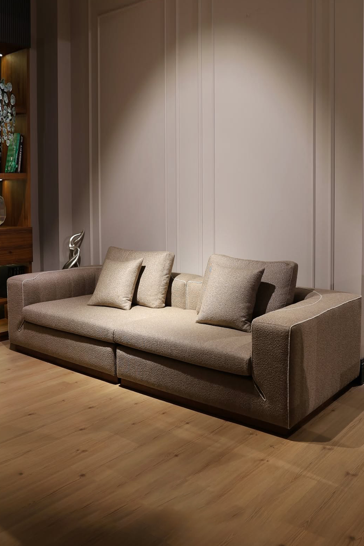 Beige sofa with cushions in a room with wooden flooring and a neutral wall.