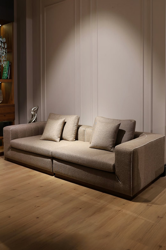 Beige sofa with cushions in a room with wooden flooring and a neutral wall.